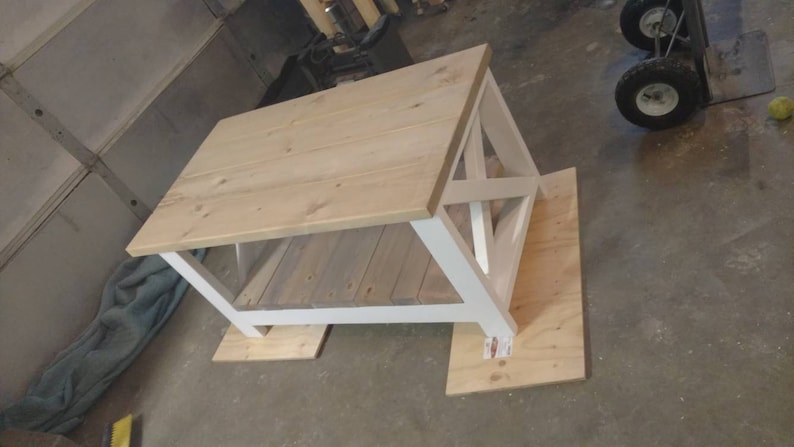 May include: White coffee table with a wooden top and a white base. The table is sitting on a wooden floor.