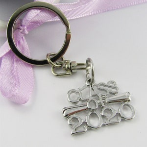May include: Silver keychain with a graduation cap and the text "Class of 2020". The keychain is attached to a silver key ring with a purple ribbon.