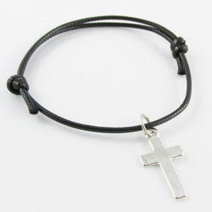 May include: A black cord bracelet with a silver cross charm.