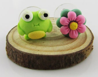 May include: A pair of green frog and pink flower earrings. The earrings are made of polymer clay and are attached to clear earring posts.