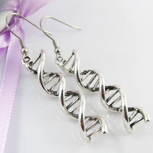 May include: A pair of silver dangle earrings featuring a double helix design, reminiscent of a DNA strand.