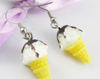 May include: A pair of silver ice cream cone earrings with white ice cream and brown chocolate sauce.