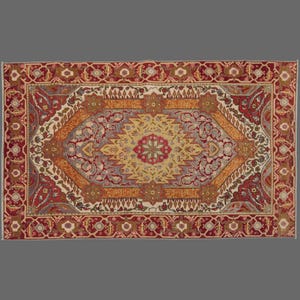 May include: A rectangular rug with a central medallion design. The rug features a complex pattern in shades of red, gold, beige, and grey. The border is a repeating floral motif in red and gold.