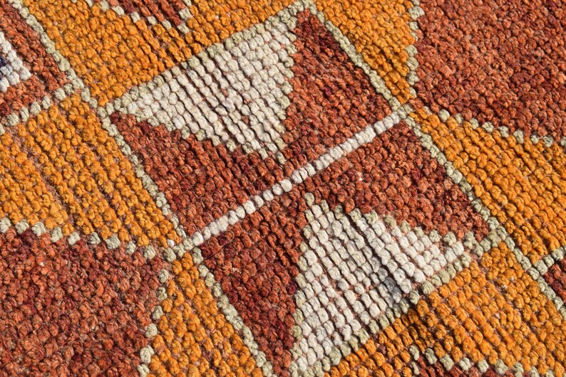 K&ouml;nnte beinhalten: Nahaufnahme eines gewebten Teppichs mit einem geometrischen Muster in Orange-, Braun- und Wei&szlig;t&ouml;nen.
