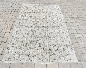 May include: A white and gray patterned rug with a floral design. The rug is made of a soft, woven material and has a distressed look.
