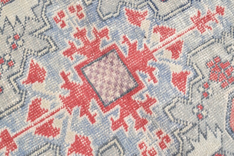 May include: A close-up of a blue and red patterned rug with a geometric design. The rug has a faded, vintage look.