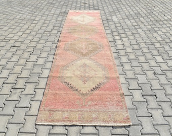 Puede incluir: Una alfombra larga y estrecha de color rosa y beige. La alfombra tiene un diseño persa tradicional con detalles intrincados.
