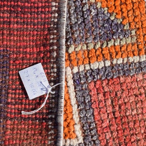 K&ouml;nnte beinhalten: Nahaufnahme eines bunten gewebten Teppichs mit einem Etikett mit der Aufschrift "6511 8" x 30" 27" x 10" 04"