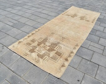 May include: A beige runner rug with a brown geometric pattern. The rug is laid out on a gray concrete surface.