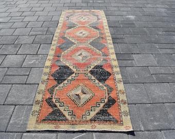 Può includere: Un tappeto runner turco vintage con un motivo geometrico in tonalità di rosso, nero e crema. Il tappeto ha un aspetto vissuto ed è perfetto per aggiungere un tocco di stile bohémien alla tua casa.
