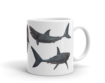 May include: White ceramic mug with a graphic of three gray sharks in different positions. The sharks are swimming in a white background.