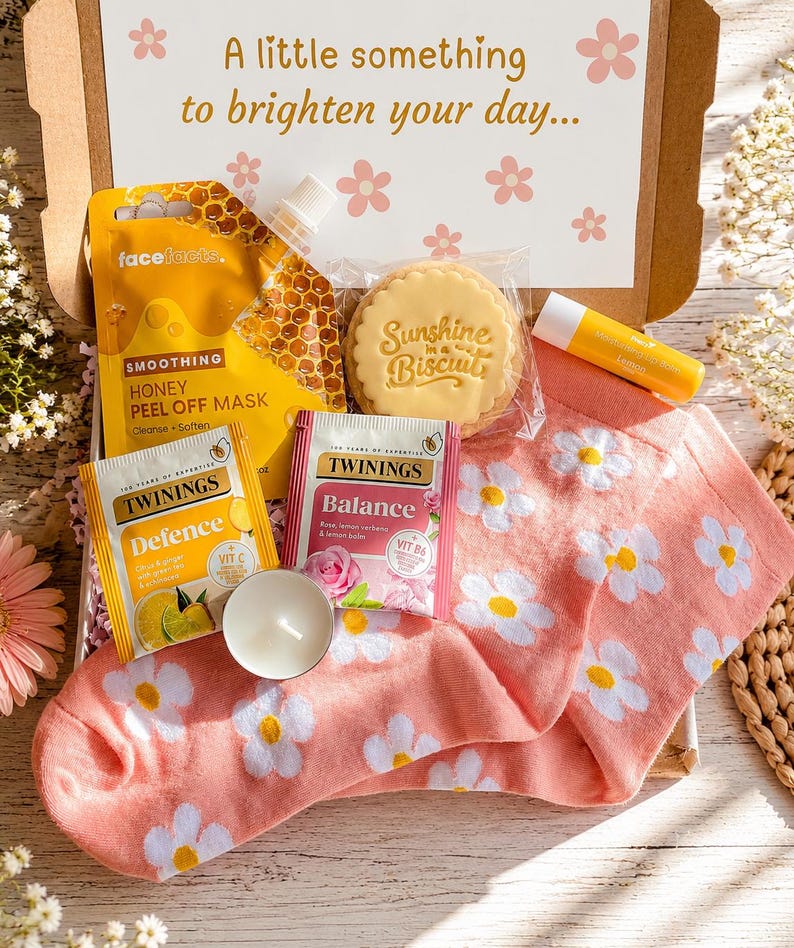 以下が含まれることがあります： Face Factsのハニーピールオフマスク、Sunshine in a Biscuitクッキー、レモンリップバーム、TwiningsのDefenceとBalanceティーバッグ、小さな白いティーライトキャンドル、そして白いデイジー柄のピンクの靴下が入ったギフトボックス。