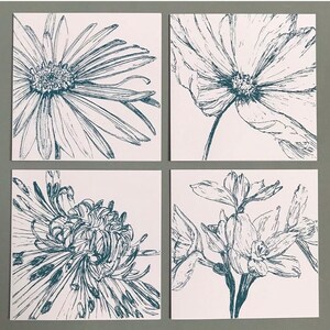 May include: Four square tiles with black and white line drawings of flowers. The tiles feature a daisy, a cosmos, a chrysanthemum, and a daffodil.