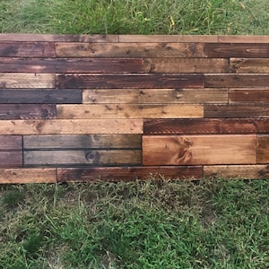 May include: A rustic wooden wall panel made of reclaimed wood planks in various shades of brown, with a natural wood grain pattern.