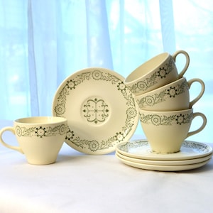 May include: Set of four vintage teacups and saucers with a green floral pattern. The cups and saucers are white with a green floral design around the rim.