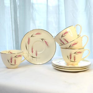 May include: Set of four vintage teacups and saucers with a pink and gold wheat design. The cups and saucers are white with a delicate floral pattern.