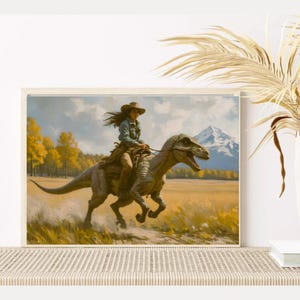 May include: A framed art print depicts a person riding a dinosaur through a field. The person wears a cowboy hat and denim shirt. The dinosaur is gray and brown. The background features a mountain and yellow trees.