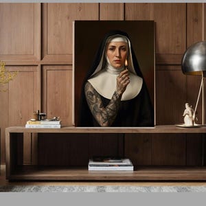 May include: A framed portrait of a nun holding a lit match. The nun is wearing a traditional black habit with a white wimple and collar. Her arm is covered in intricate tattoos. The background is a dark, warm color.