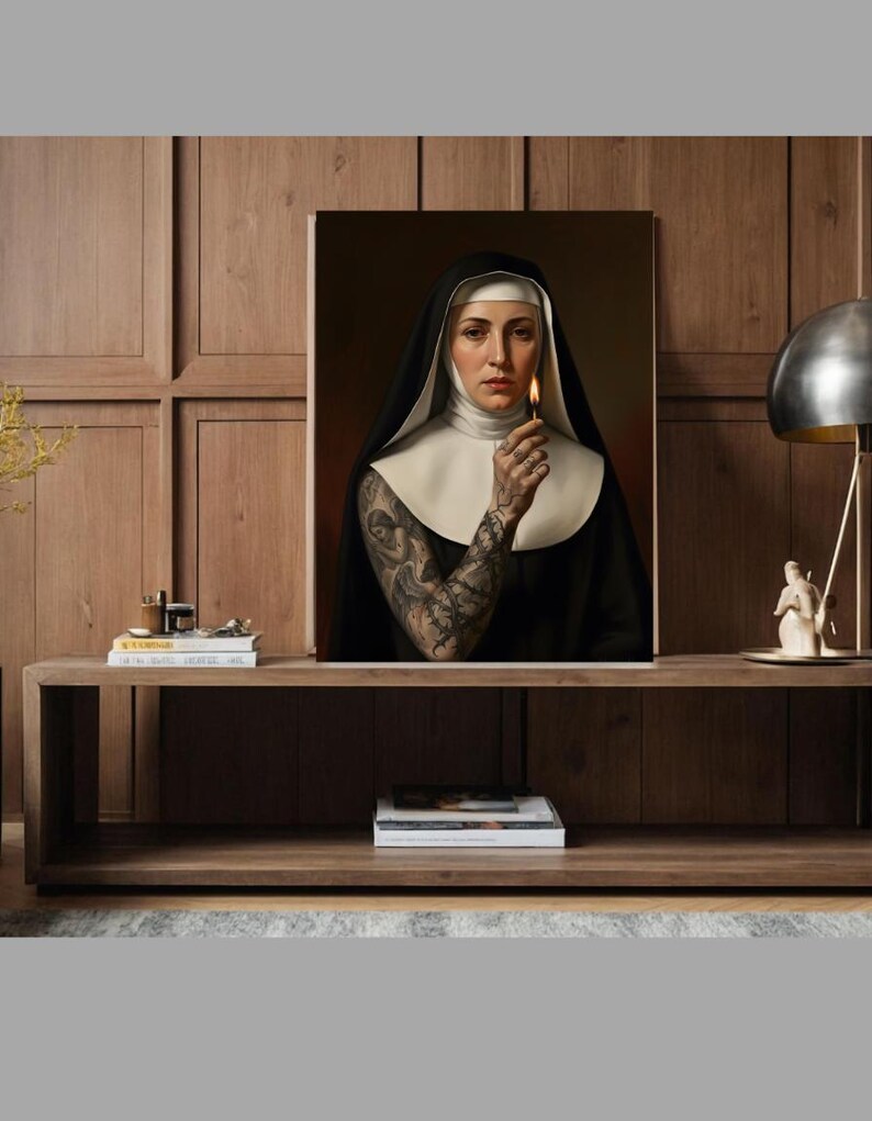 May include: A framed portrait of a nun holding a lit match. The nun is wearing a traditional black habit with a white wimple and collar. Her arm is covered in intricate tattoos. The background is a dark, warm color.