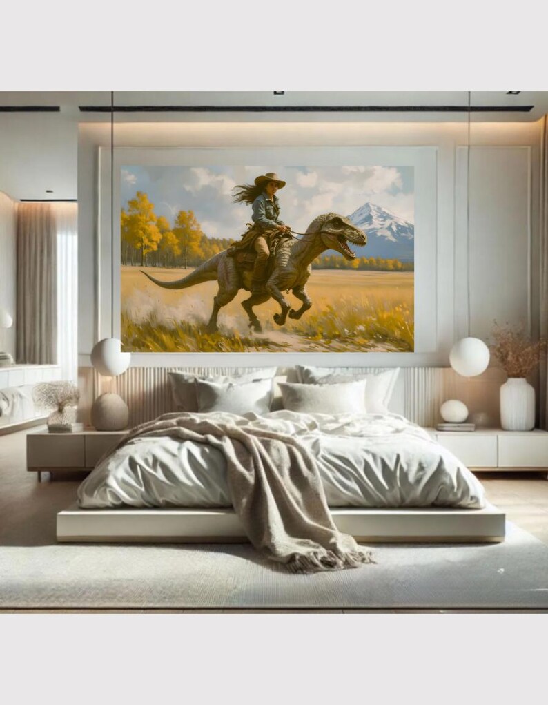 May include: A large framed painting depicts a person riding a dinosaur through a field. The person wears a hat and western attire. The background shows a mountain range and yellow trees. The painting is displayed above a bed with white bedding.