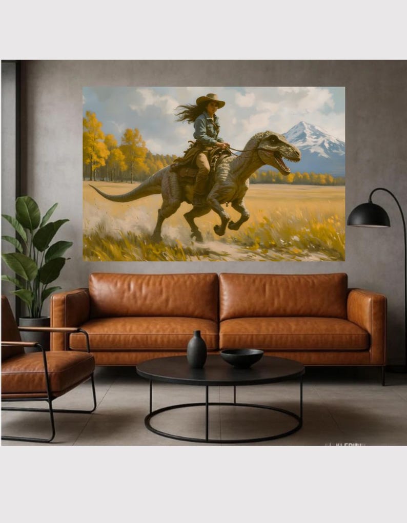 May include: A large canvas print depicts a person riding a dinosaur through a field. The person wears a cowboy hat and denim shirt. The dinosaur is gray and brown. The background features yellow trees, a mountain, and a blue sky. The print is displayed above a brown leather sofa.