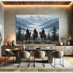 Op de afbeelding: Een groot landschapsschilderij toont drie figuren te paard die uitkijken over een bergketen. Het kunstwerk gebruikt blauw, groen en bruin, met besneeuwde toppen op de achtergrond. Het schilderij wordt tentoongesteld boven een eettafel met stoelen.