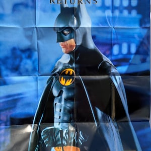 May include: A blue and black poster featuring Batman from the movie Batman Returns. The poster has the title "Batman Returns" and the Sega Game Gear logo.
