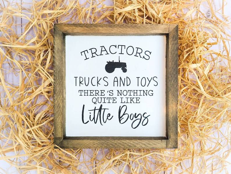 Puede incluir: Un letrero de madera enmarcado con el texto "TRACTORES CAMIONES Y JUGUETES NO HAY NADA COMO LOS NI&Ntilde;OS PEQUE&Ntilde;OS" en letras negras. Una silueta de un tractor est&aacute; encima del texto. El letrero est&aacute; rodeado de paja.