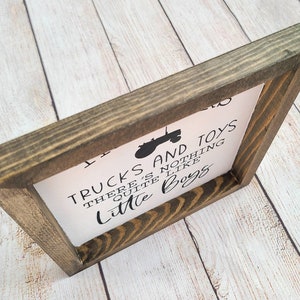 Puede incluir: Un letrero de madera enmarcado con el texto "Trucks and Toys, There's nothing quite like Little Boys" en letras negras. Tambi&eacute;n se incluye un gr&aacute;fico de tractor negro. El marco es de color marr&oacute;n oscuro.