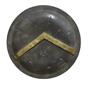 Può includere: Uno scudo rotondo grigio con un design a chevron dorato. Lo scudo presenta numerose piccole indentature circolari.