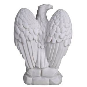 Op de afbeelding: Een witte adelaar sculptuur met uitgespreide vleugels, met gedetailleerde veermotieven. De sculptuur staat op een getextureerde basis. Het materiaal lijkt solide en ondoorzichtig, met de nadruk op de vorm en textuur van de vogel.