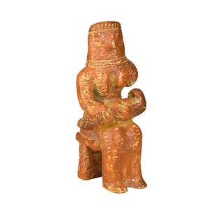 May include: A terracotta-colored figurine of a seated figure with a cylindrical headdress and detailed facial features. The sculpture has a textured surface and appears to be handmade. The figure is seated on a simple stool.