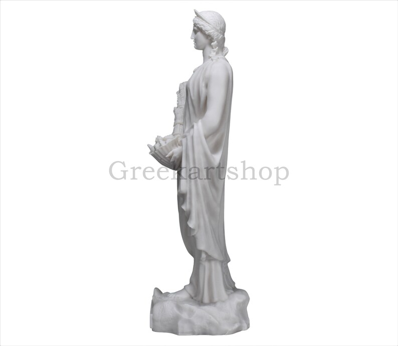 May include: A white marble statue of a classical figure, seen in profile, holding an object. The figure wears a draped garment and a headpiece. The statue is on a white background. The text "Greenartshop" is visible.