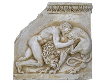 May include: A beige stone-colored wall relief plaque depicting a muscular figure wrestling a lion. The scene features a decorative border at the top and the Greek text HPAKΛHΣ inscribed above the figure. The sculpture has a weathered finish.