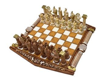 May include: A wooden chessboard with a white and brown checkered pattern. The chess pieces are made of white and brown ceramic and are shaped like Greek gods and goddesses. The board is decorated with gold accents.