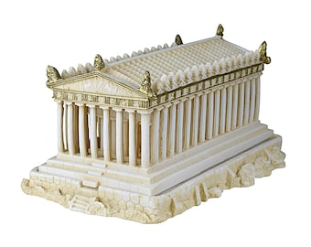 May include: A detailed ivory-colored miniature replica of an ancient Greek temple, featuring numerous columns, a sloped roof, and gold accents. The model sits on a textured base, showcasing architectural details.