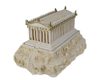 Könnte beinhalten: Ein Miniaturmodell des Parthenon-Tempels mit cremefarbenen Säulen und einem Dach mit goldfarbenen Akzenten. Das Bauwerk steht auf einem strukturierten, felsigen Sockel, der eine geschnitzte Treppe zum Tempeleingang enthält.