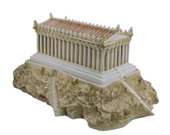 May include: A white and gold miniature replica of the Temple of Poseidon, a Greek temple with columns, on a rocky base.