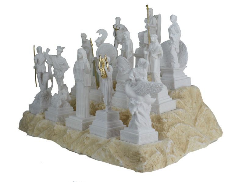 May include: A white alabaster sculpture set of the twelve Greek gods and goddesses on a white and beige stone base. The sculptures are all standing on individual bases and are arranged in a semi-circle.