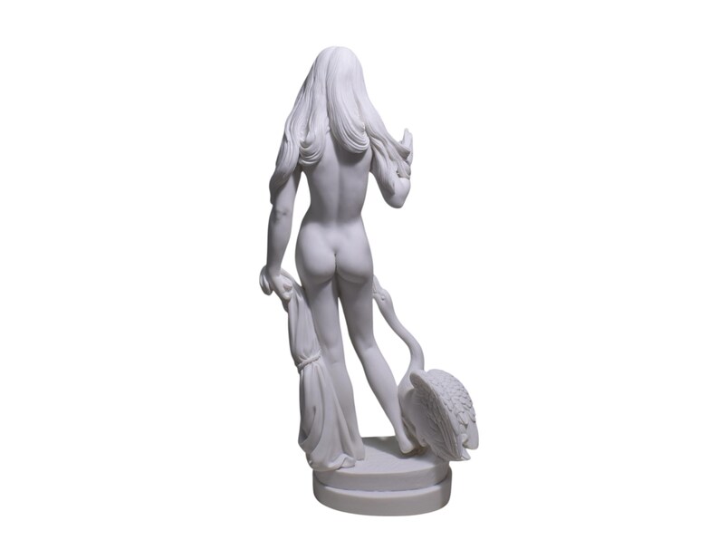 May include: White marble statue of a woman standing with a swan. The woman is nude and has long flowing hair. The swan is standing on its legs and has its wings spread out.