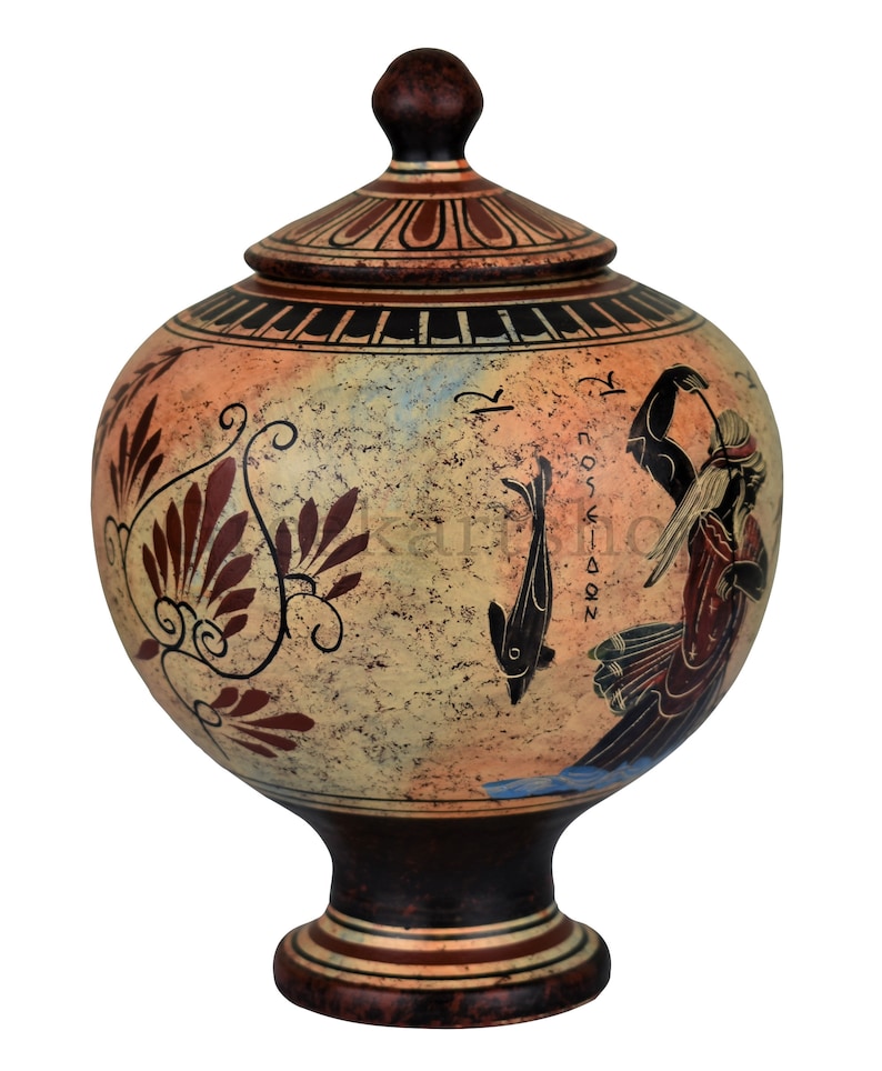May include: A ceramic Greek amphora with a lid, decorated with a red and black floral design, a fish, and a figure with a staff. The amphora is on a white background.