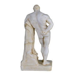 May include: A marble statue of a muscular figure, viewed from the back. The statue is off-white with detailed musculature and a draped cloth. It stands on a rectangular base, showcasing classical art.
