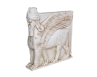 Puede incluir: Escultura detallada en blanco roto de un Lamassu, deidad protectora de la antigua Asiria. El toro alado tiene cabeza humana con barba y tocado detallados. La escultura está tallada con intrincados detalles.