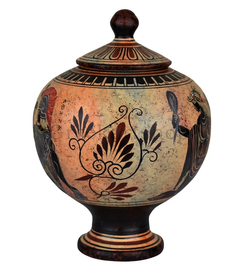 May include: A hand-painted ceramic vase with a lid, featuring a stylized floral design and a scene of a woman holding a mirror. The vase is decorated in black, red, and white on a beige background. The vase has a round body and a tall, slender base.