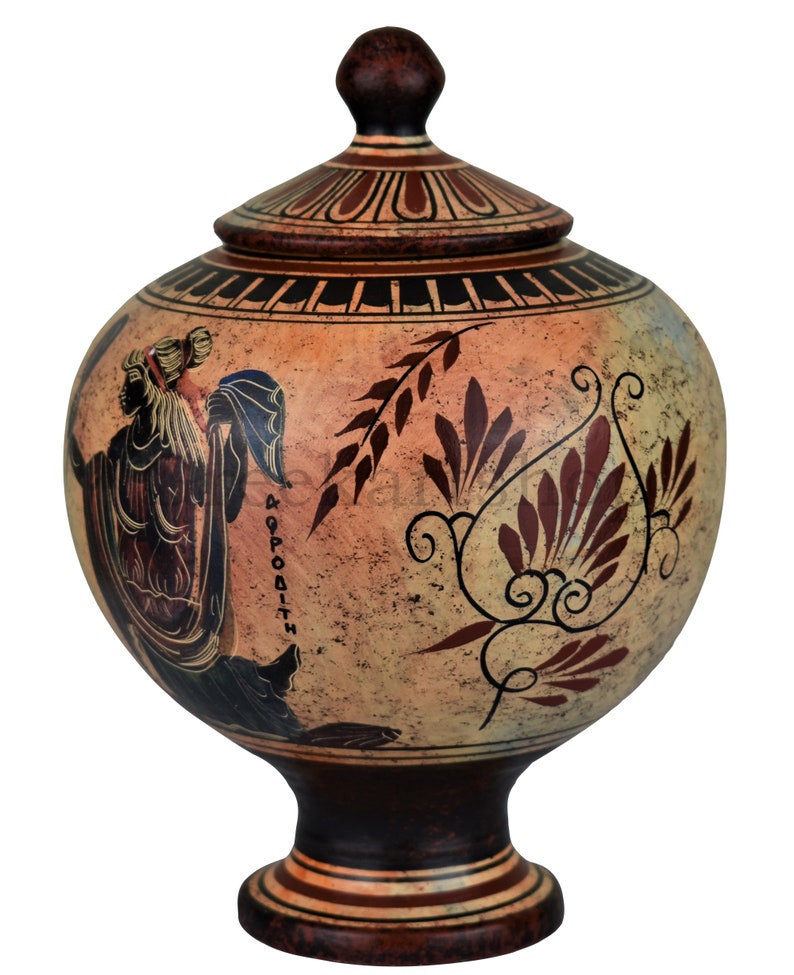 May include: A ceramic Greek style urn with a lid, painted with a figure of a woman holding a staff and a floral design. The urn is decorated with red, black, and white paint on a beige background. The text "&Alpha;&Phi;&Rho;&Omicron;&Delta;&Iota;&Tau;&Eta;" is written on the side of the urn.