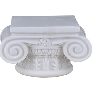 May include: A white, Ionic-style column capital. The capital features a square top, a detailed frieze with floral and leaf patterns, and prominent scroll-shaped volutes on either side. The design is symmetrical and classic.