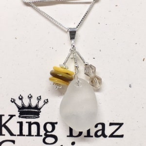 May include: A silver chain necklace with a pendant featuring a white sea glass charm, a stack of yellow and brown glass beads, and a clear crystal bead.