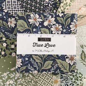 May include: A collection of fabric squares in various floral and geometric patterns. The dominant colors are navy, green, and cream. A ruler is placed over a fabric square with the text "True Love" by Lella Boutique.