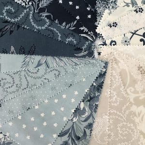 Peut inclure: Une collection d'&eacute;chantillons de tissu dispos&eacute;s en &eacute;ventail, pr&eacute;sentant une palette de couleurs bleu marine, bleu ardoise, cr&egrave;me et beige. Les motifs incluent des fleurs complexes, de petites feuilles d'&eacute;rable blanches et des pois.