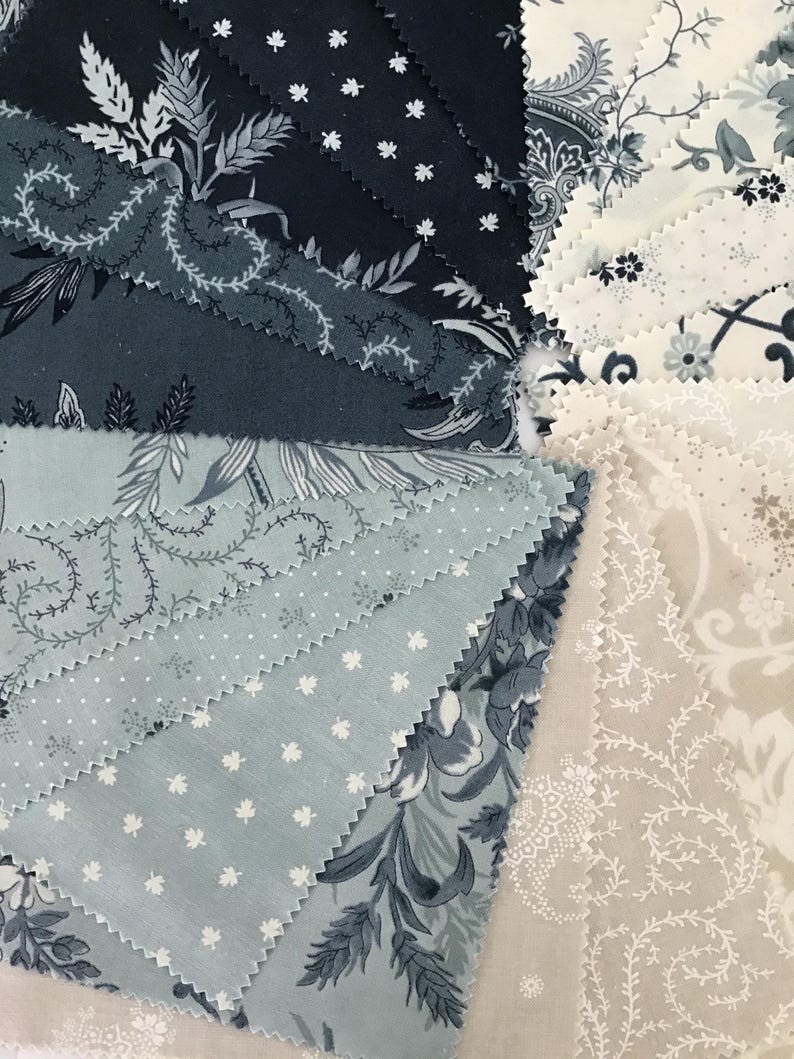 Peut inclure: Une collection d'&eacute;chantillons de tissu dispos&eacute;s en &eacute;ventail, pr&eacute;sentant une palette de couleurs bleu marine, bleu ardoise, cr&egrave;me et beige. Les motifs incluent des fleurs complexes, de petites feuilles d'&eacute;rable blanches et des pois.